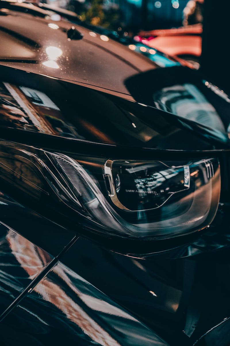 Close-up of a shiny black car's headlight in Munich, highlighting design and elegance.